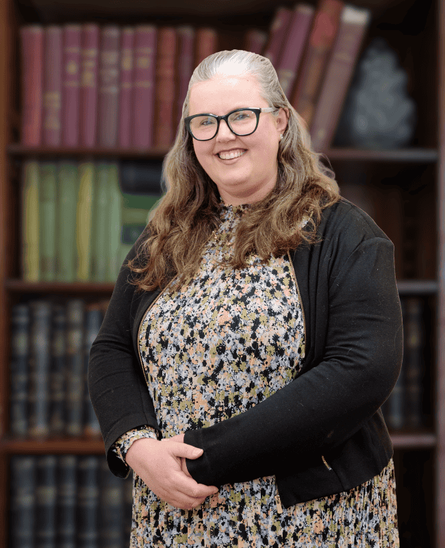 Rachael Adams — French Burt Partners Lawyers, New Zealand standing in front of a book case
