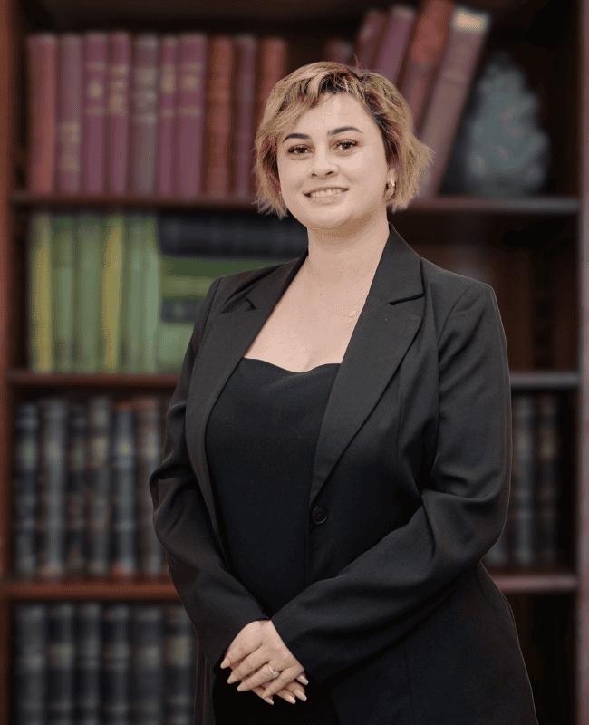 Rei Cooper — French Burt Partners Lawyers, New Zealand standing in front of a book case