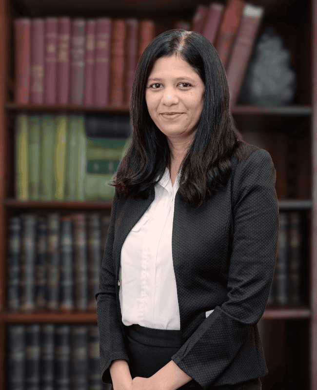Shweta Raj — French Burt Partners Lawyers, New Zealand standing in front of a book case